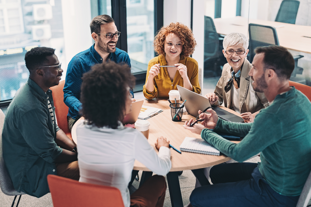 A diverse group of six professionals collaborate around a table in an office.
